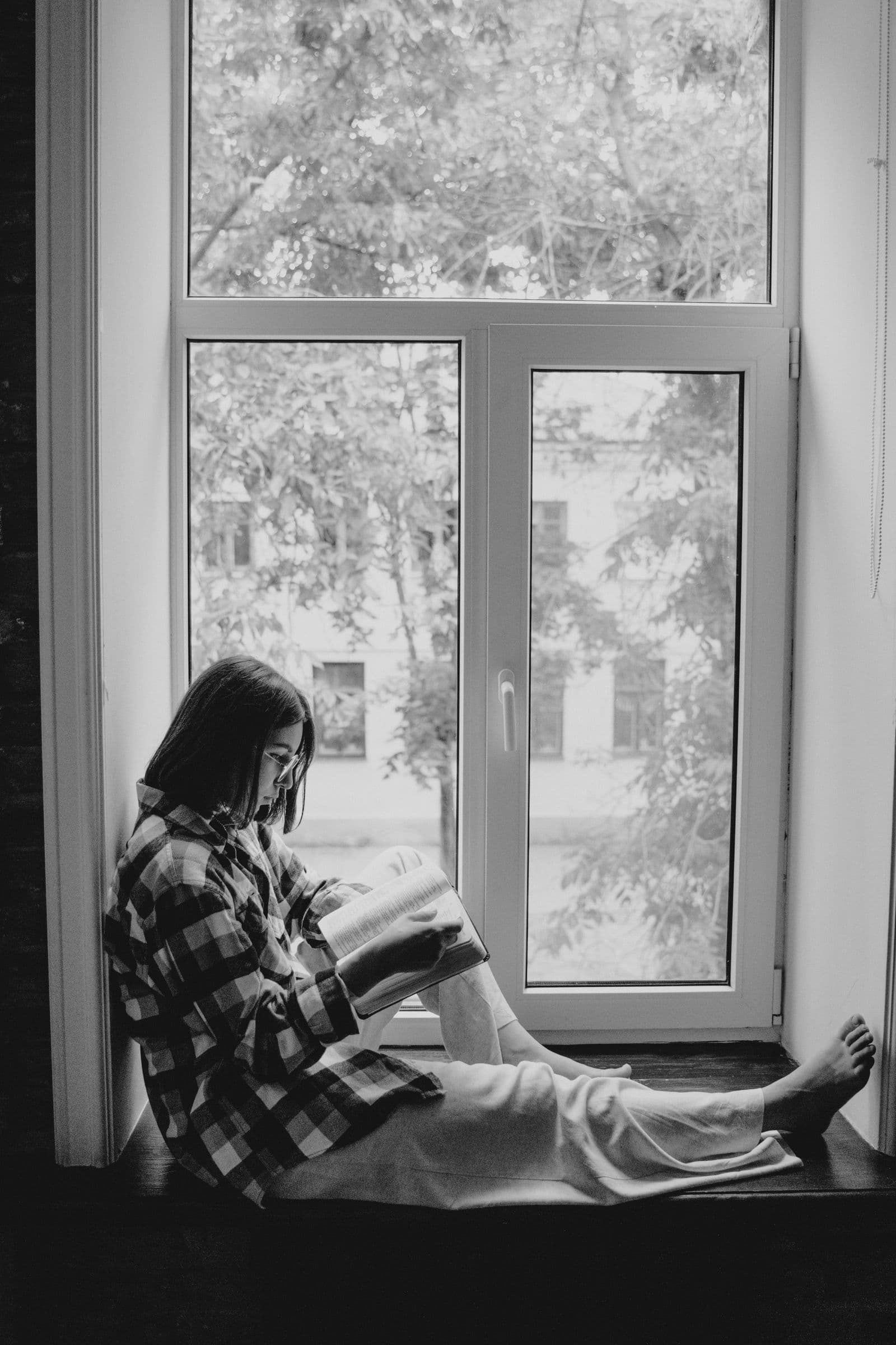 A woman reading beside a window
